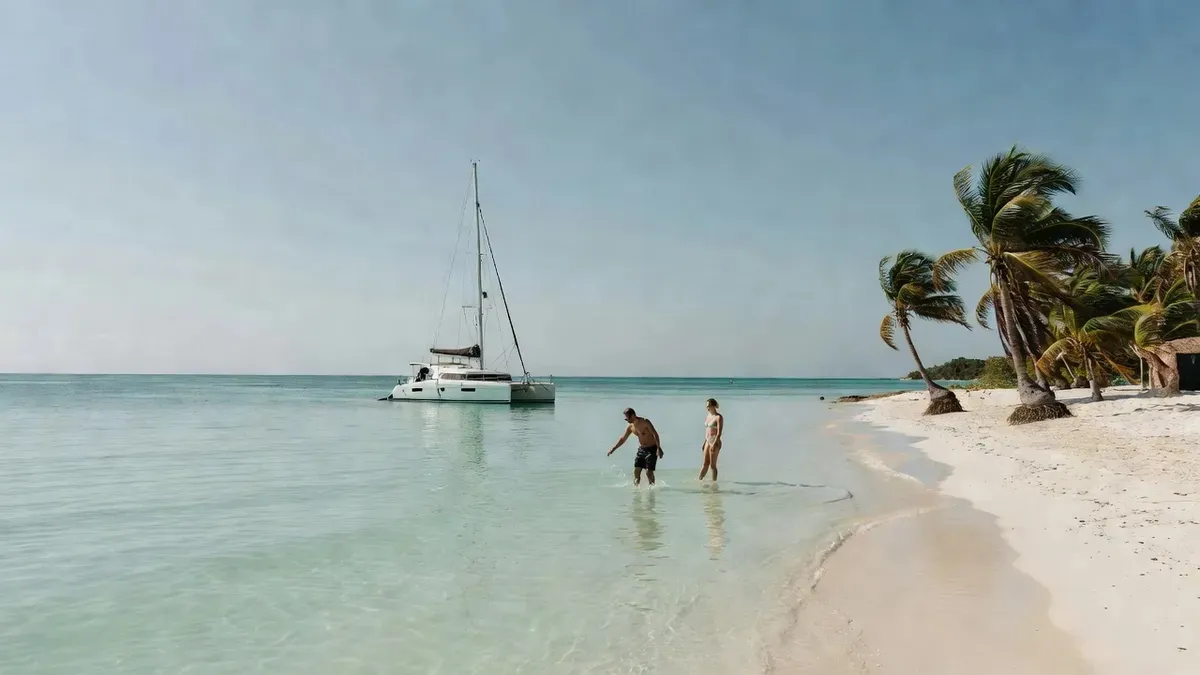 A sailing catamaran anchored off the white sand and turquoise shallows of Playa Norte on an Isla Mujeres Playa del Carmen boat tour, Mexico