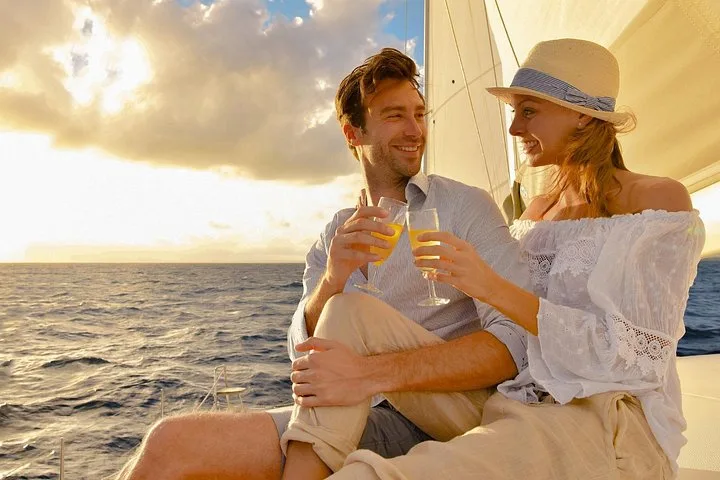 Couple toasting on the deck of a sailing catamaran at sunset on a Riviera Maya sunset Playa del Carmen boat tour, Mexico